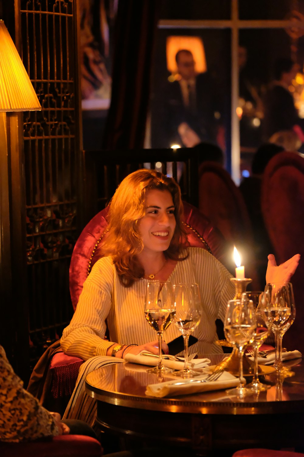 a woman sitting at a table with wine glasses