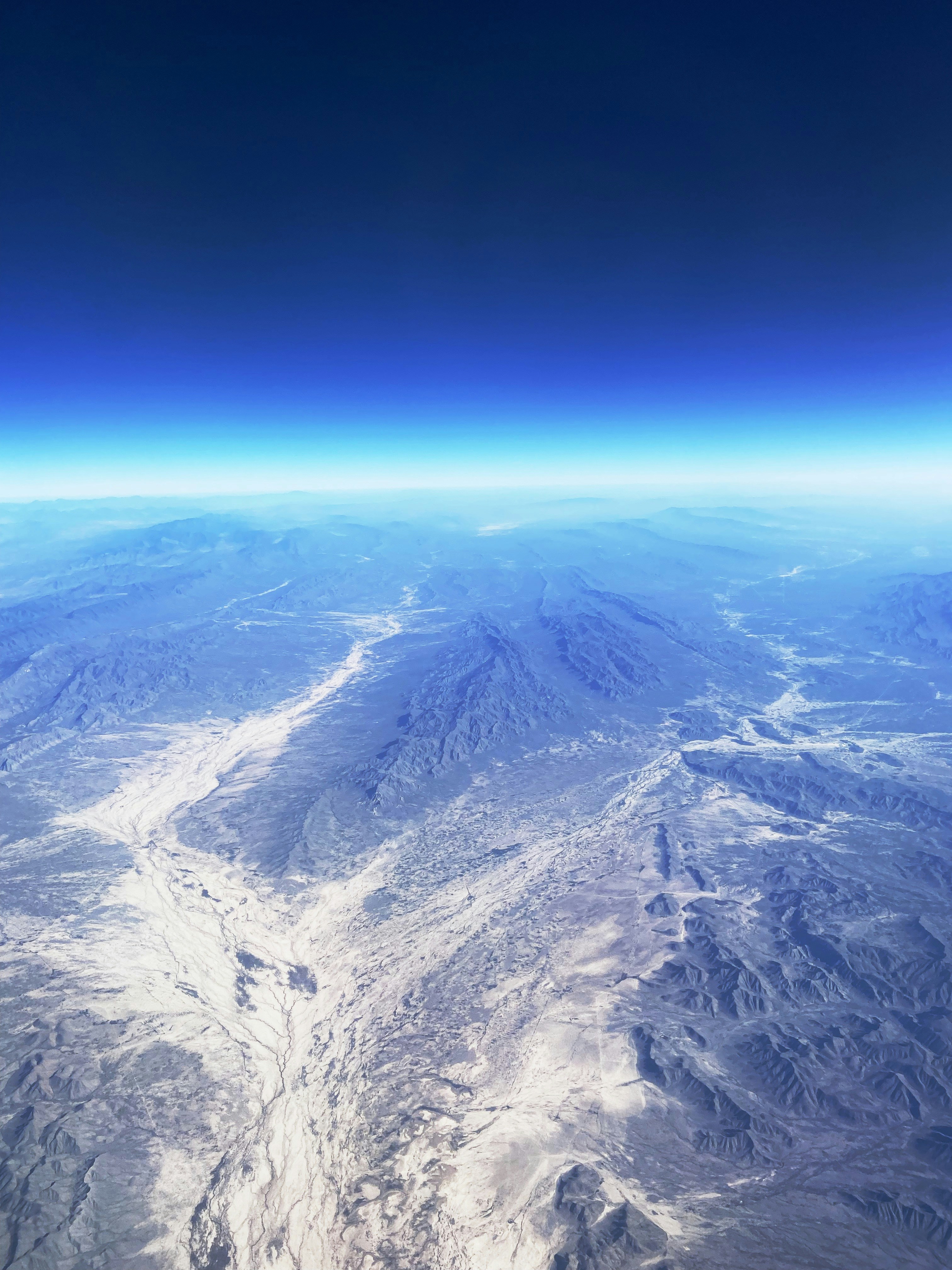 Small aircraft landing on a remote desert airstrip surrounded by Namibian wilderness, flat rocky terrain and distant mountain ranges under clear blue sky