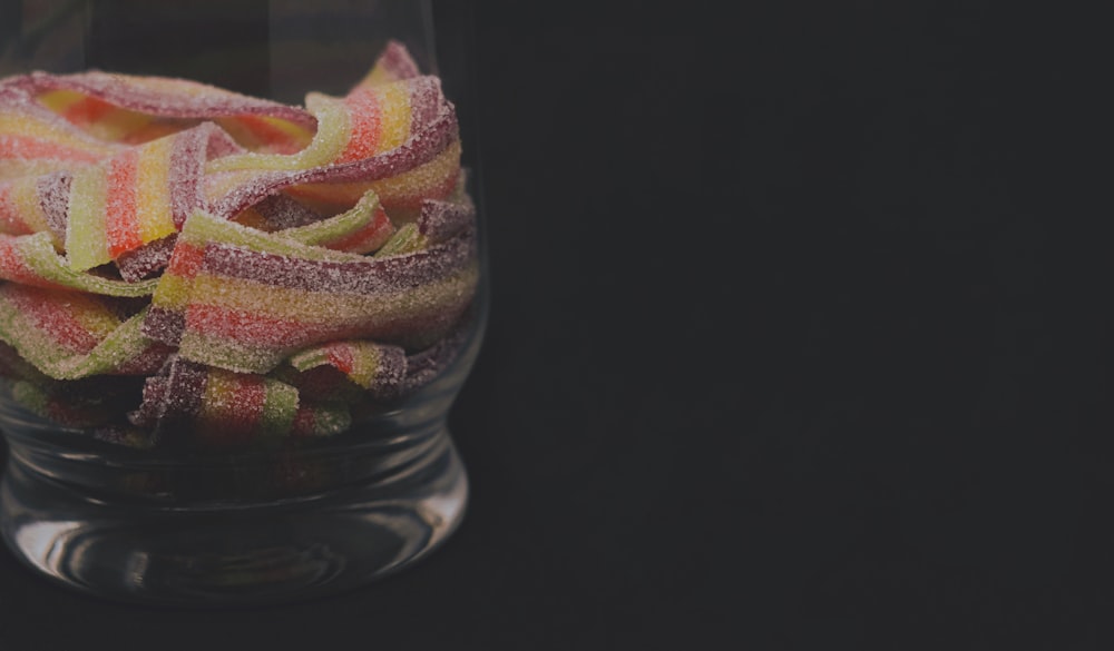 a glass filled with candy sitting on top of a table