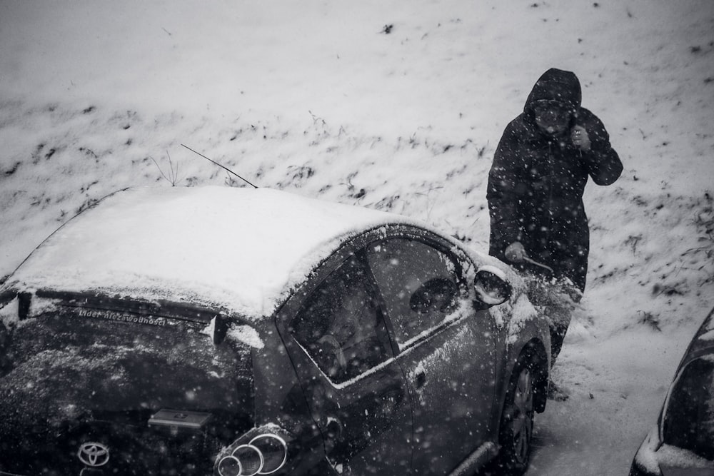 a man standing next to a car covered in snow
