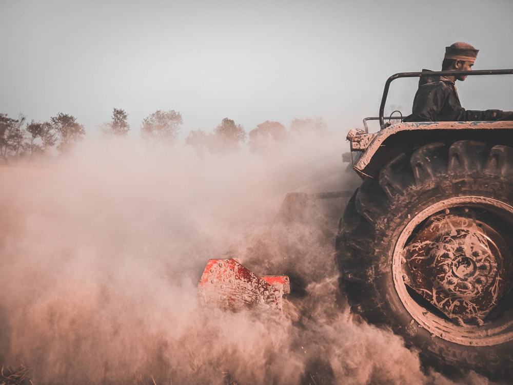 a man driving a large truck through a dusty field