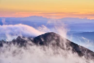A misty mountain range stretching under a pastel sunrise sky.