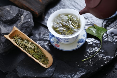 a cup of green tea next to a container of green tea