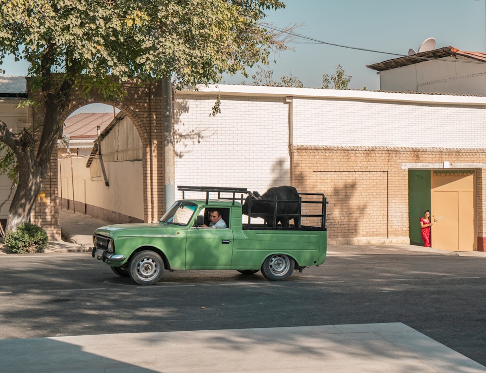 a green pick up truck parked in front of a building