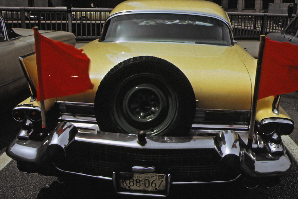 a yellow car with red flags on the back of it