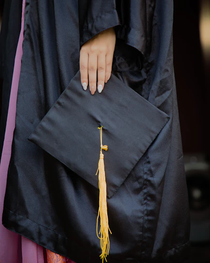 a woman's hand holding a graduation cap and tassel