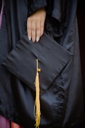 Close-up of hands holding a graduation cap and a job market report.