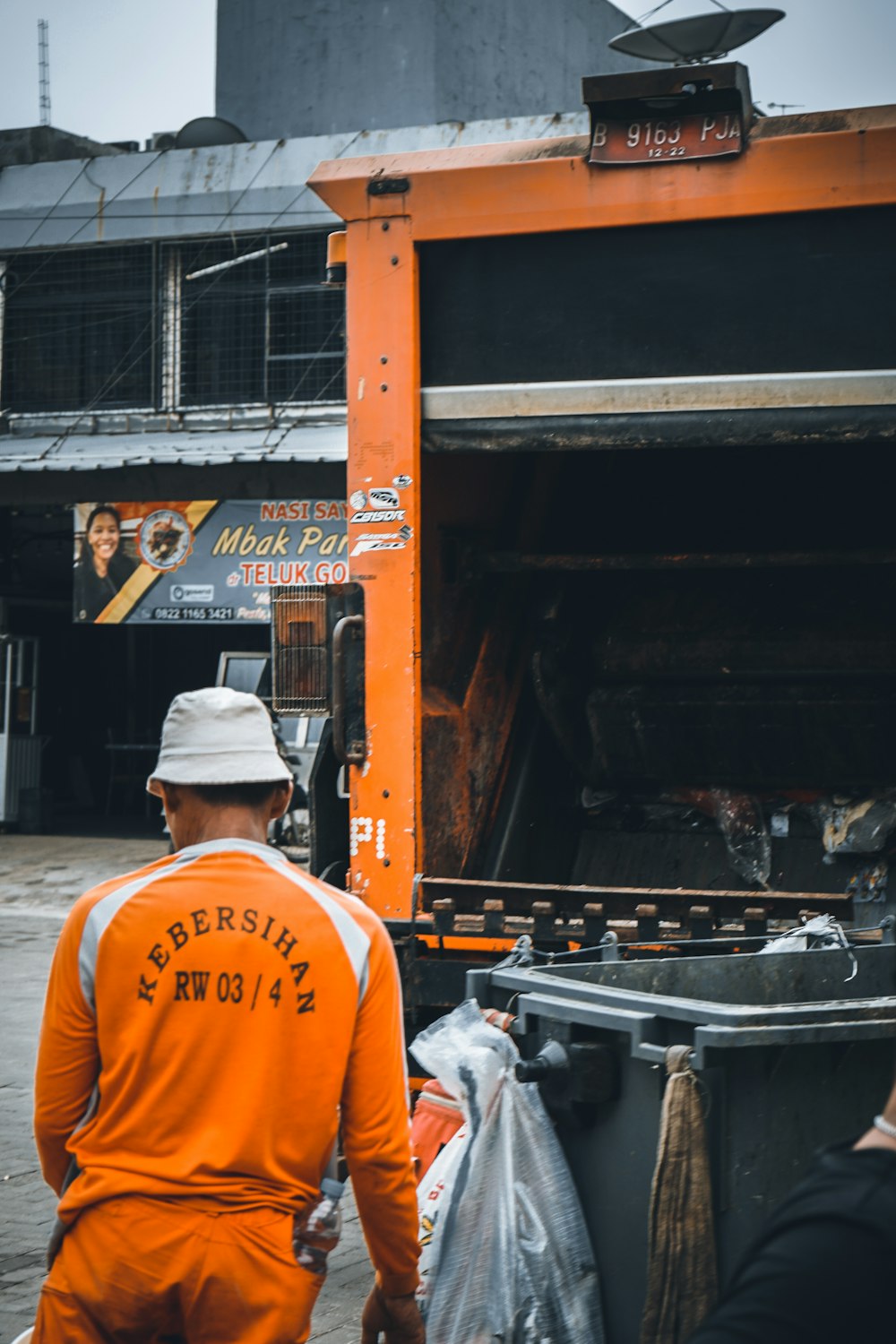 um homem de pé ao lado de um caminhão de lixo