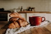 A cozy scene with mugs and everyday objects featuring subtle French heritage designs on a rustic wooden table.