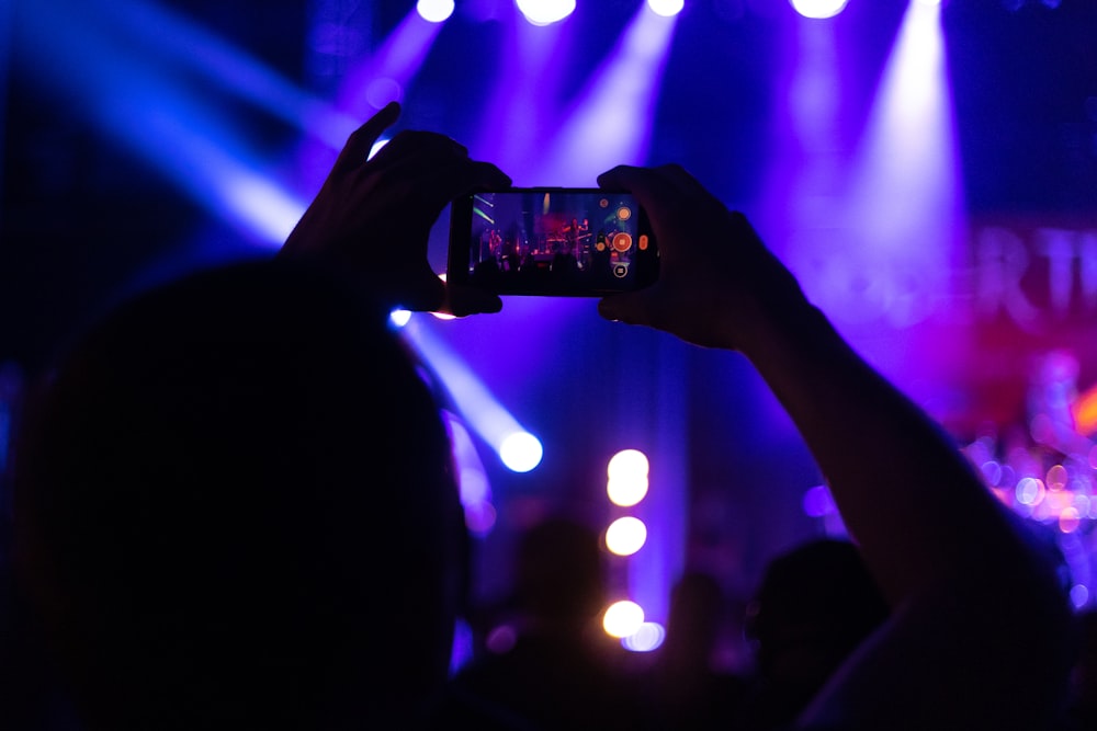 a person taking a picture of a concert with a cell phone