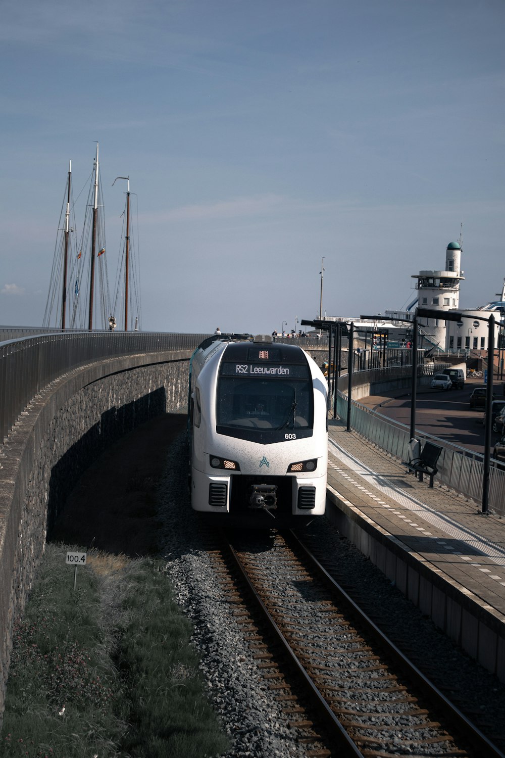 a white train traveling down train tracks next to a bridge