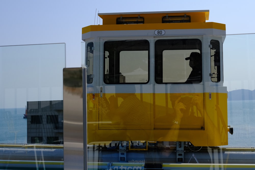 a yellow and white train traveling past a large body of water