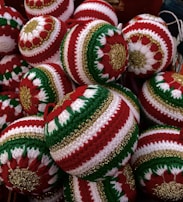 A collection of intricately crocheted Christmas ornaments featuring red, green, and white patterns with gold accents. Each ornament is uniquely designed with symmetrical patterns that stand out due to the vibrant color contrast.
