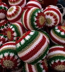A collection of intricately crocheted Christmas ornaments featuring red, green, and white patterns with gold accents. Each ornament is uniquely designed with symmetrical patterns that stand out due to the vibrant color contrast.