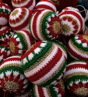 A collection of intricately crocheted Christmas ornaments featuring red, green, and white patterns with gold accents. Each ornament is uniquely designed with symmetrical patterns that stand out due to the vibrant color contrast.