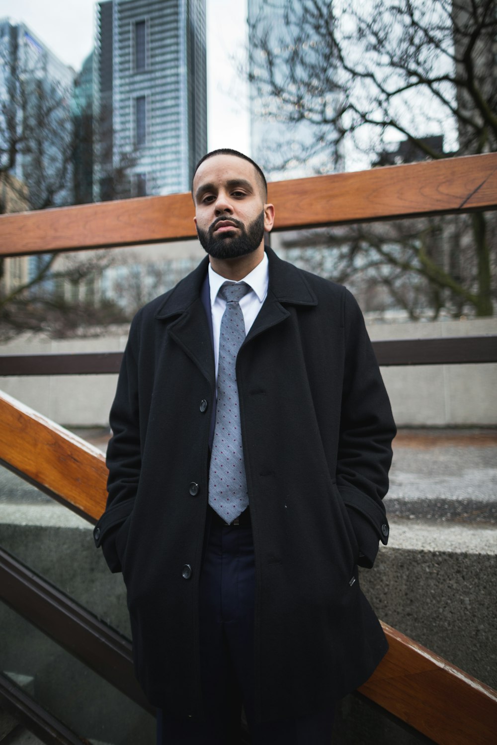 a man in a coat and tie standing on some stairs