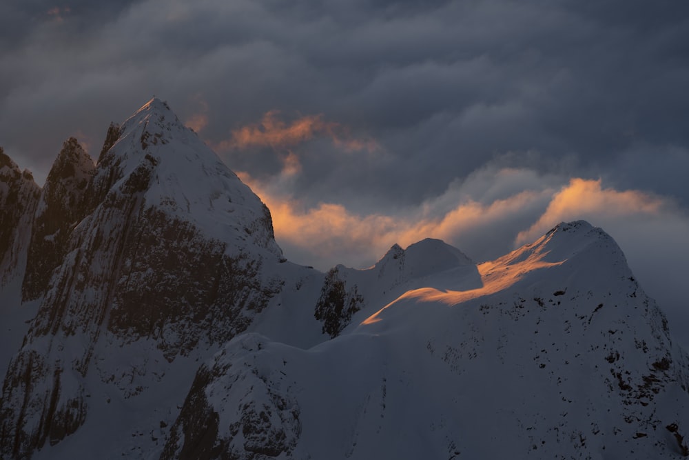 a mountain covered in snow under a cloudy sky