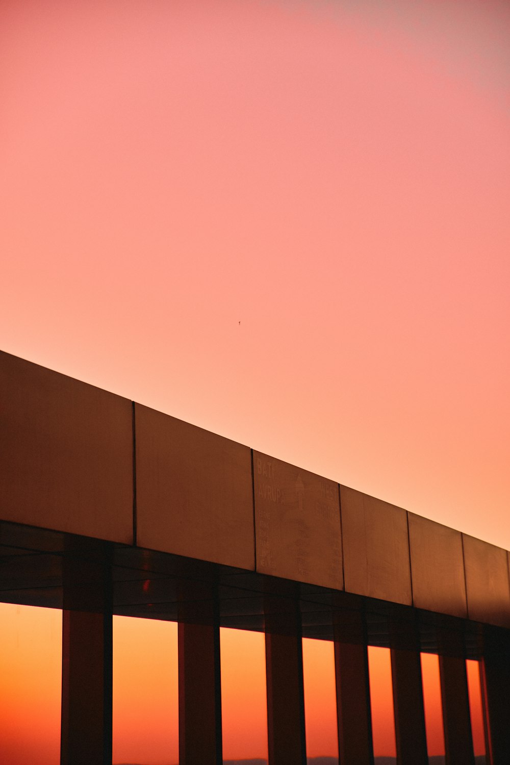 an airplane is flying over a bridge at sunset