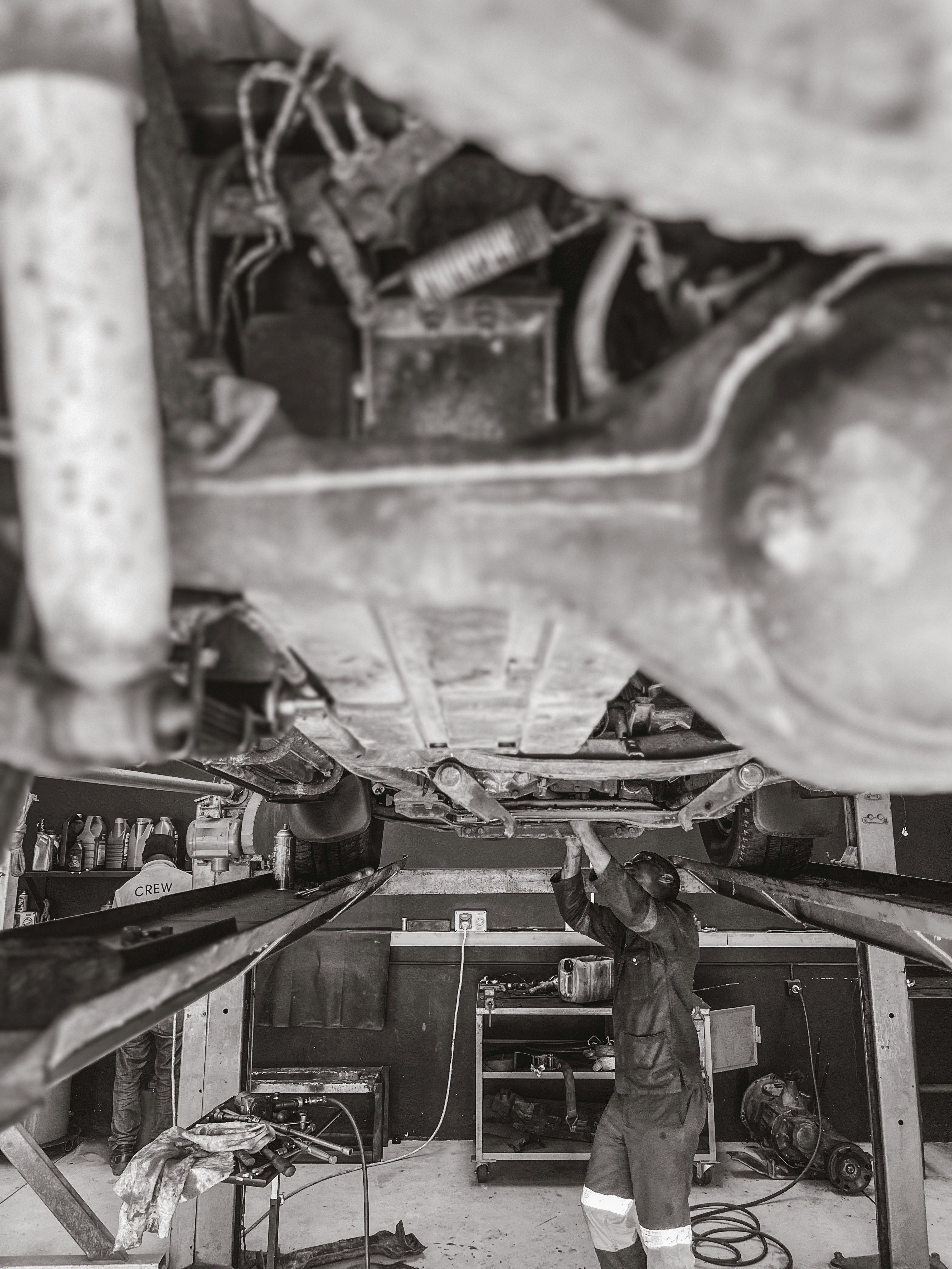 a black and white photo of a man working on a vehicle