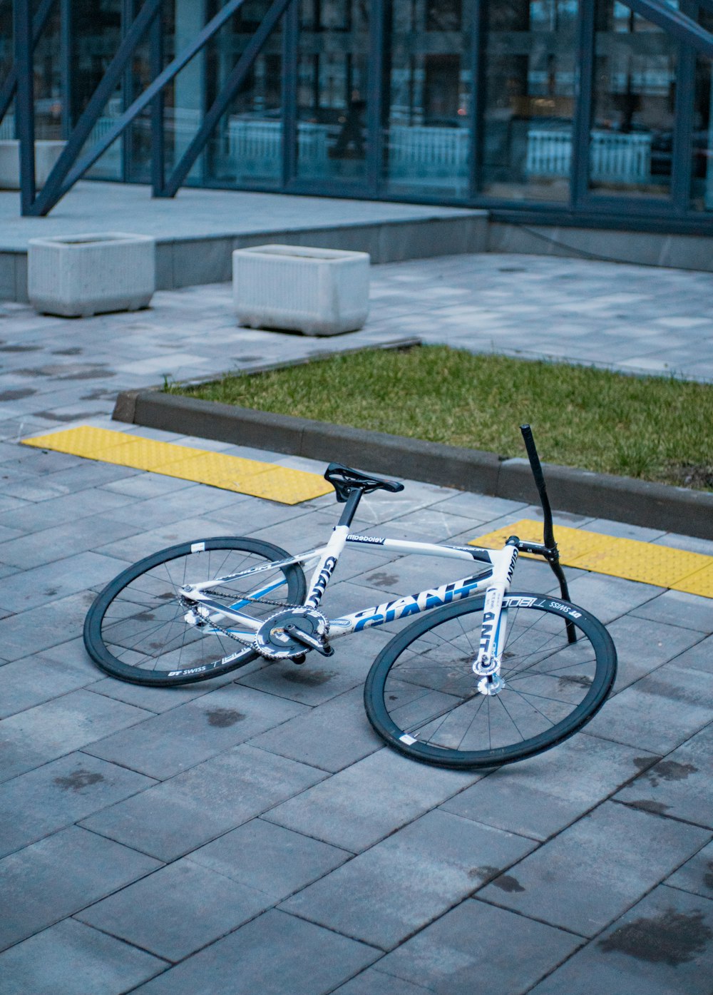 a white and blue bike parked on a sidewalk