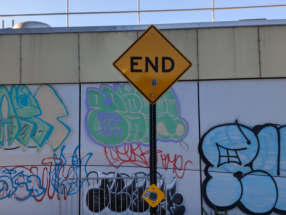 a street sign in front of a wall covered in graffiti