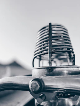 A grainy, analog noir style close-up of a vintage microphone casting a soft shadow on a textured black background.
