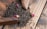 A pile of loose black tea leaves mixed with small pink rosebuds sits on a wooden surface. There is a wooden scoop partially visible, used to gather the tea leaves.