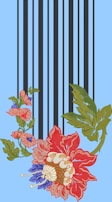 An ornate floral embroidery design features large red, blue, pink, and green flowers intertwined with leaves and vertical black stripes on a light blue background.