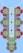An intricate embroidery design featuring red and brown flowers with green leaves arranged symmetrically along a central panel with a checkered and lace pattern. Three black buttons are evenly spaced down the center against a light blue background.