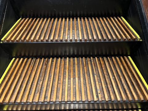 Two wooden escalator steps arranged in a neatly spaced, parallel alignment. The steps have a combination of yellow and brown tones, with metal edges visible around the wooden slats.