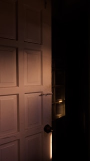 a light shines on a door in a dark room