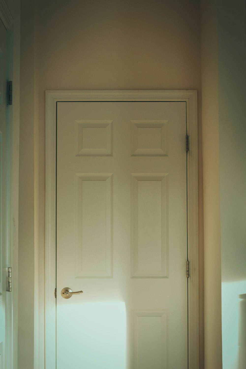 a white door in a room with a light coming through it