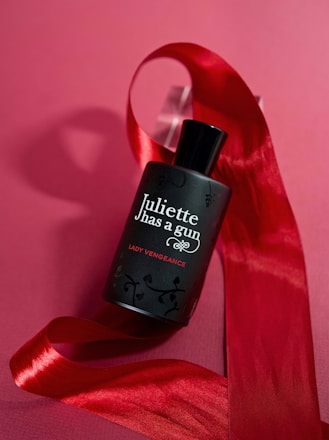 a bottle of perfume sitting on top of a red ribbon
