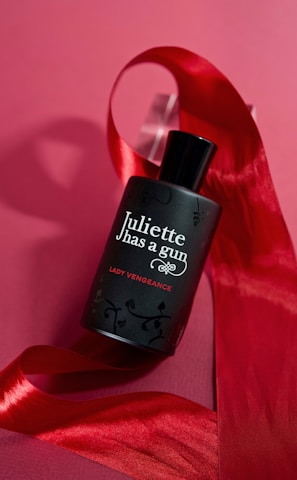 a bottle of perfume sitting on top of a red ribbon