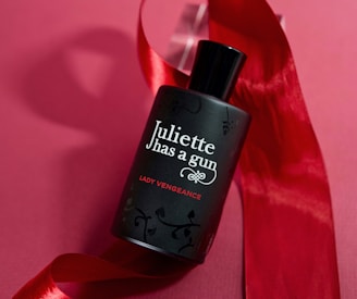 a bottle of perfume sitting on top of a red ribbon