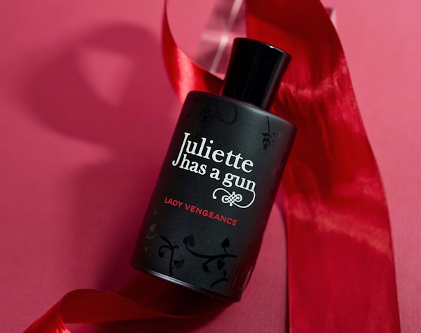 a bottle of perfume sitting on top of a red ribbon