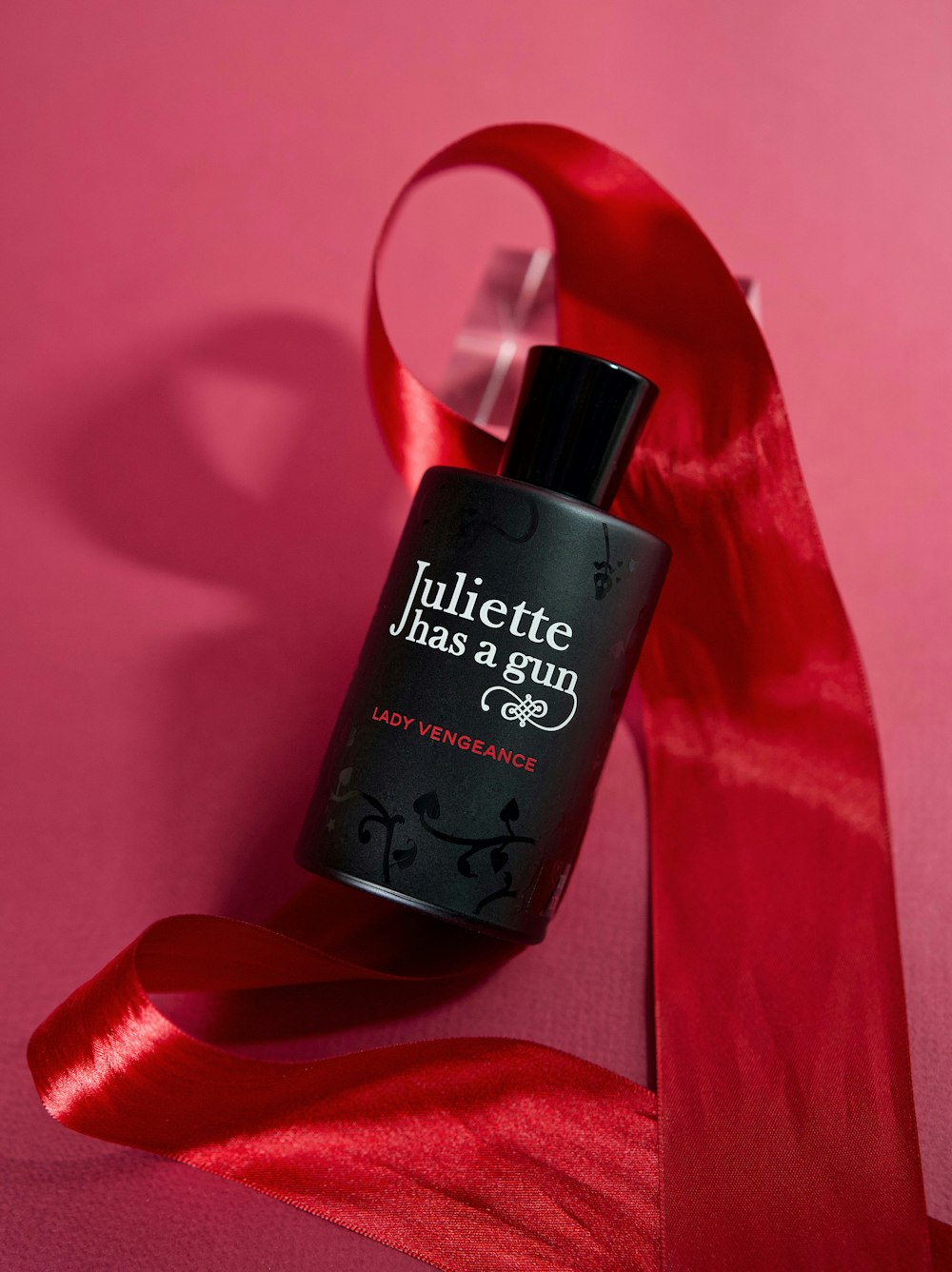 a bottle of perfume sitting on top of a red ribbon