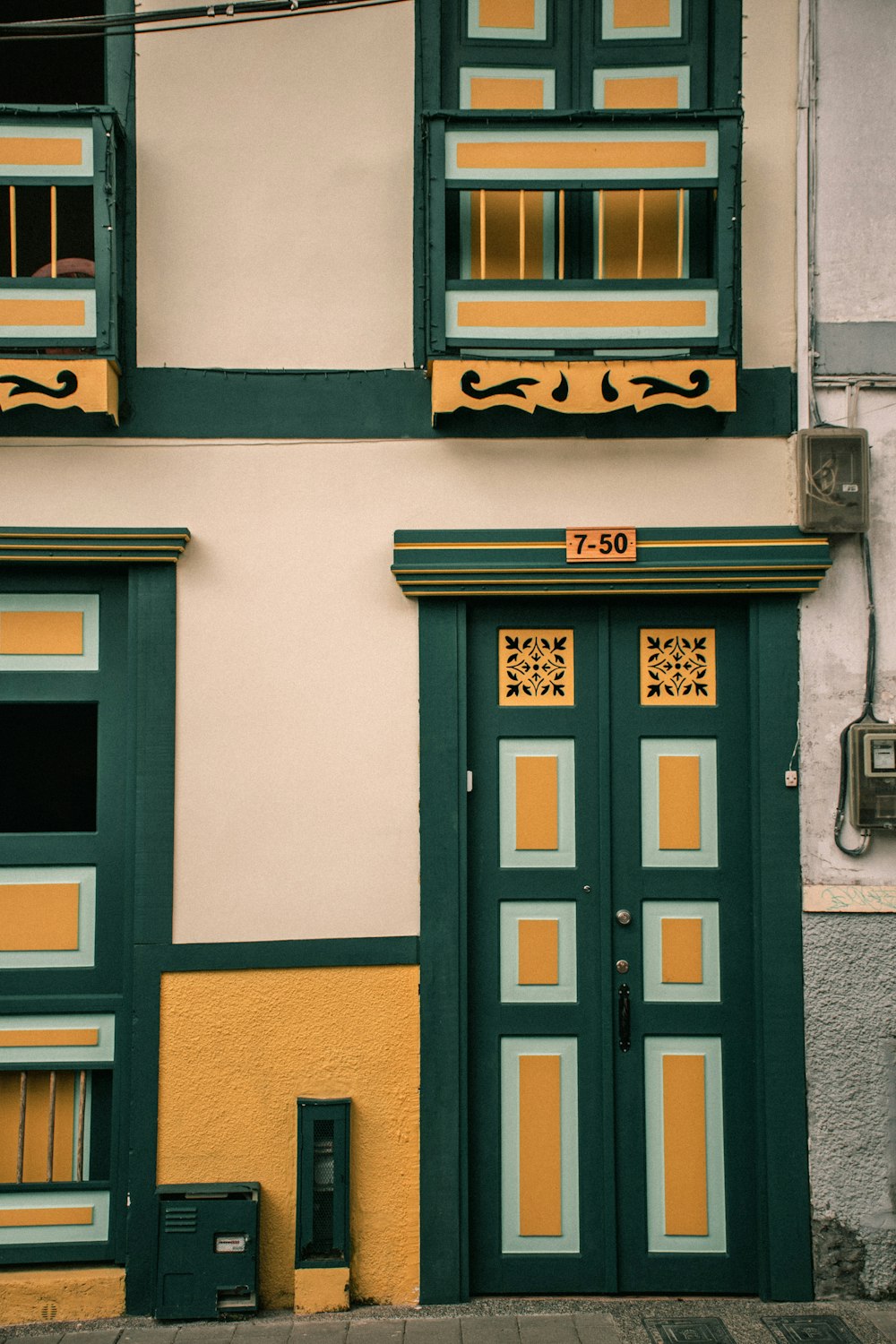 a green and yellow building with two windows