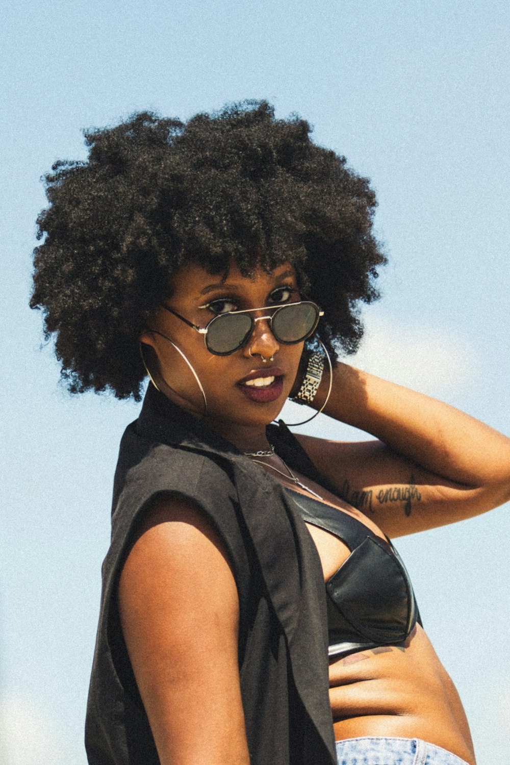 a woman in a bikini top and sunglasses talking on a cell phone