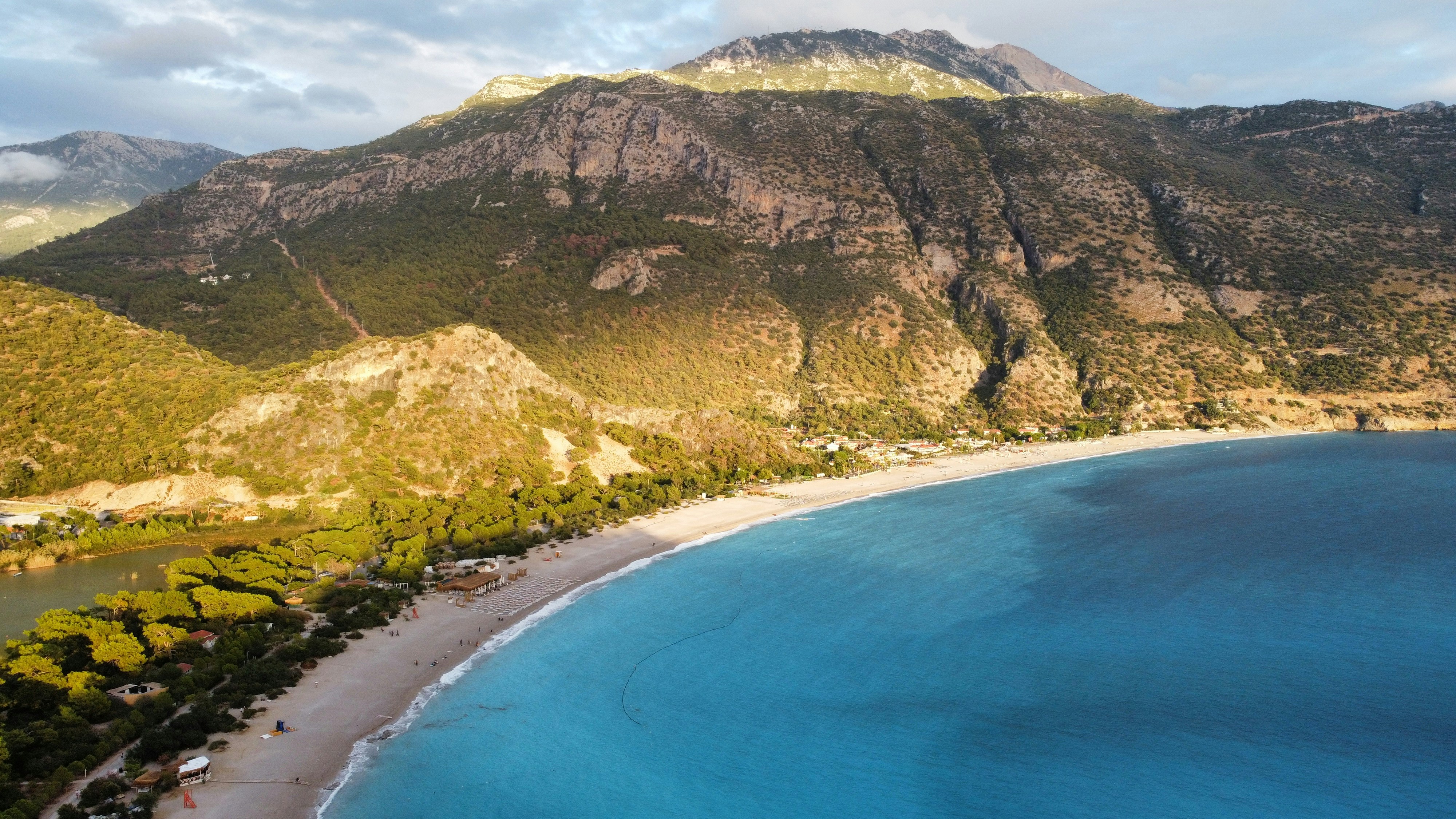 an aerial view of a beach with a mountain in the background