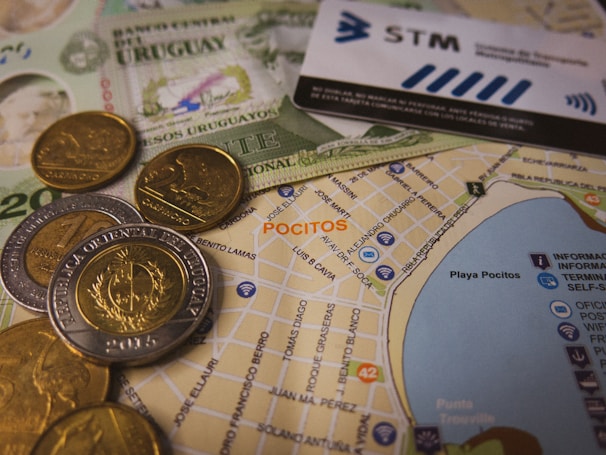 A detailed view of Uruguayan currency notes and coins alongside a map highlighting the area of Pocitos. There is also a public transportation card visible, indicating directions or locations.