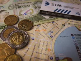 A detailed view of Uruguayan currency notes and coins alongside a map highlighting the area of Pocitos. There is also a public transportation card visible, indicating directions or locations.