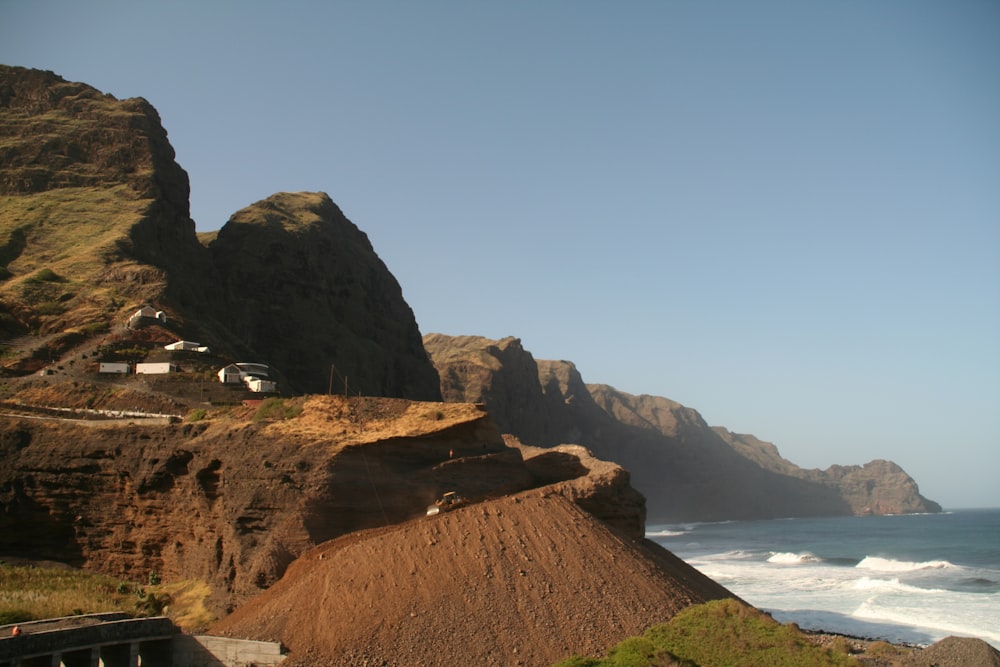 a cliff with a house on top of it next to the ocean