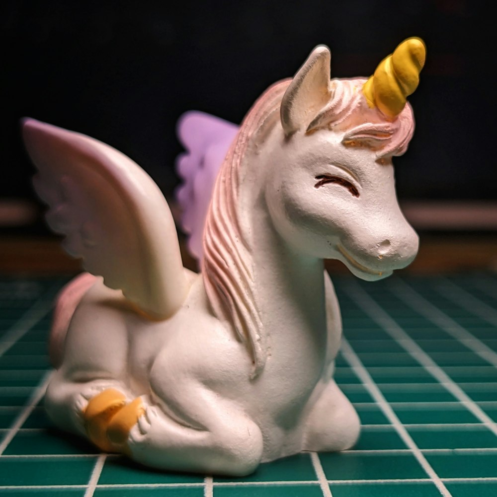 a white ceramic unicorn figurine with a yellow horn