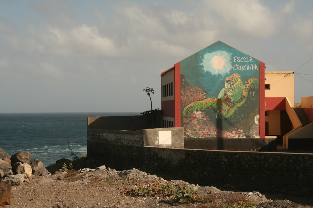 a mural on the side of a building next to the ocean