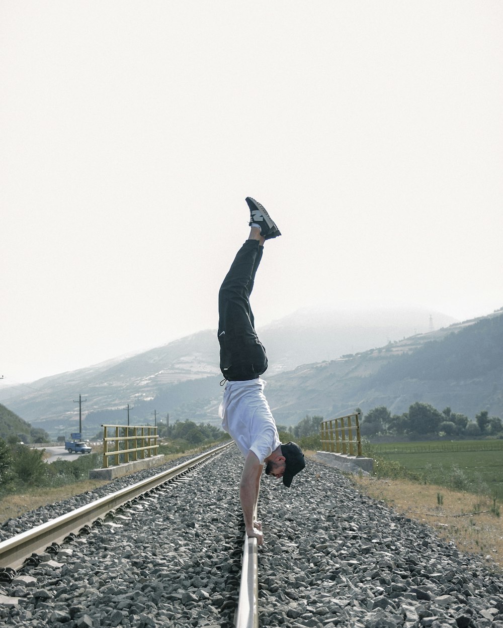 um homem fazendo um handstand em um trilho de trem