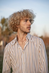 a man with curly hair wearing a striped shirt