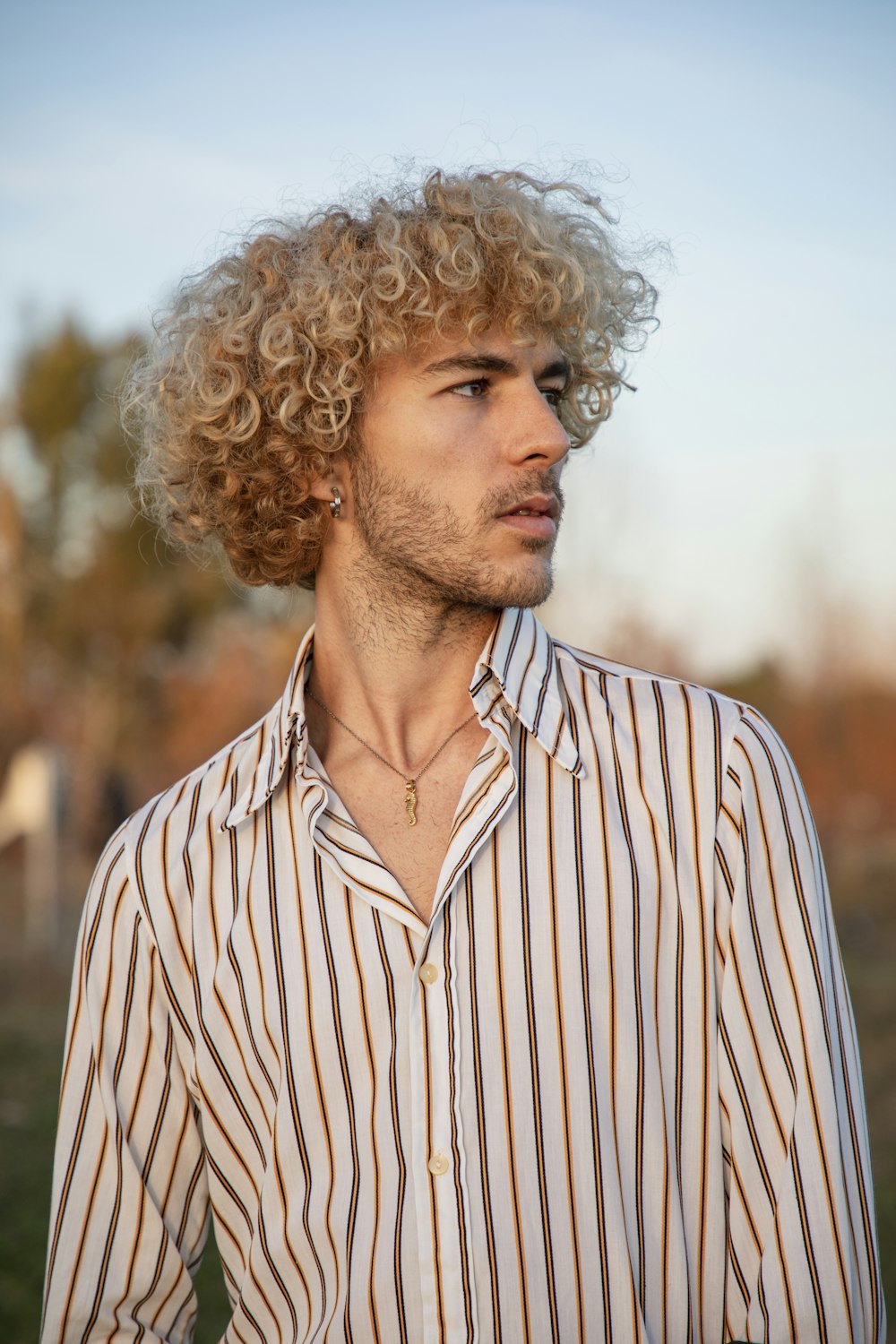 um homem com cabelo encaracolado vestindo uma camisa listrada