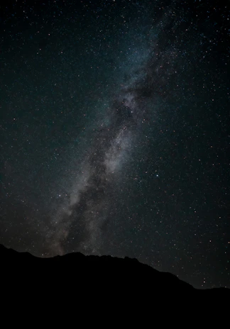 A stunning view of the Milky Way stretching across a clear night sky over a quiet desert landscape.