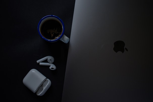 AirPods Pro 3 resting beside a smartphone and coffee cup on a cozy desk setup.